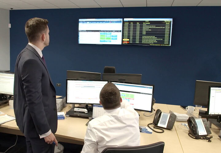 Control room with staff managing journey data using Microlise transportation management software.