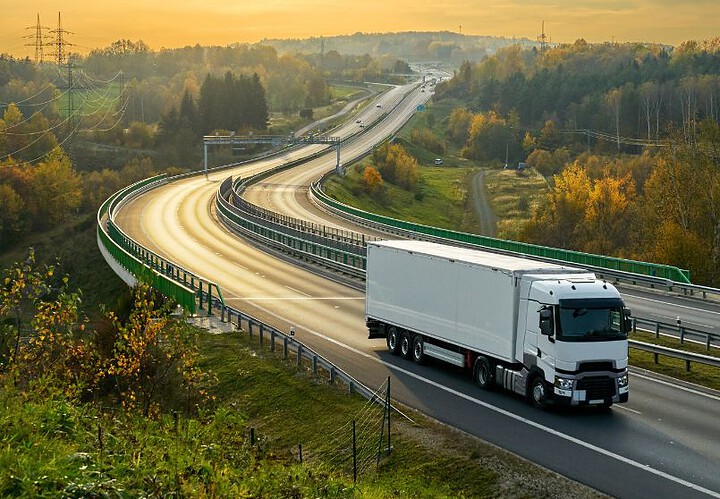 An image of a truck travelling along a winding highway during sunset, illustrating advanced journey management solutions.