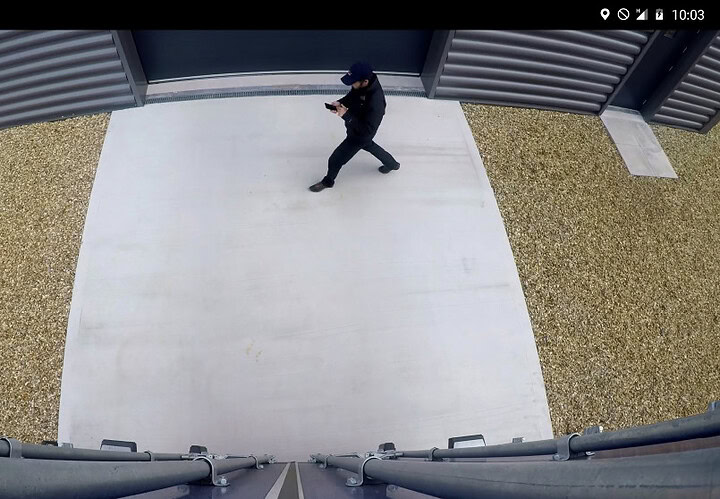 L'homme utilisant un smartphone devant un bâtiment industriel, illustrant la gestion de flotte et la technologie de suivi en temps réel de Microlise.