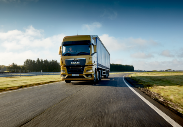 Man lorry driving on a quiet road using transport management system