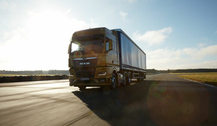 an orange MAN lorry driving on the road using transport management system (TMS)