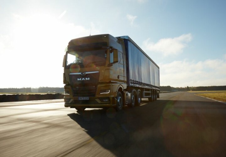 an orange MAN lorry driving on the road using transport management system (TMS)