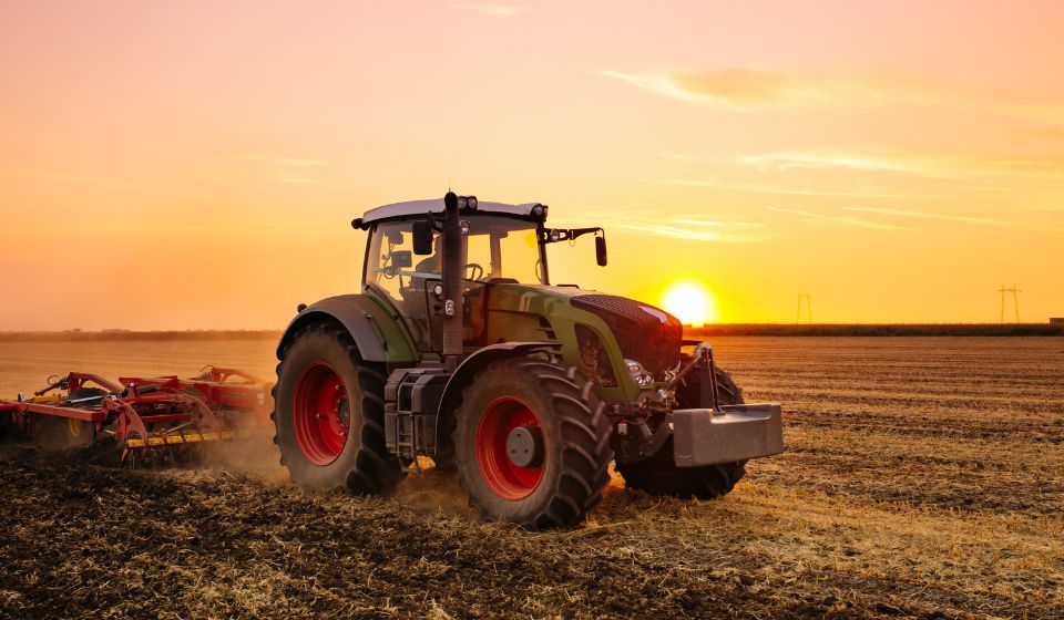 tractor harvesting with the sun in the background