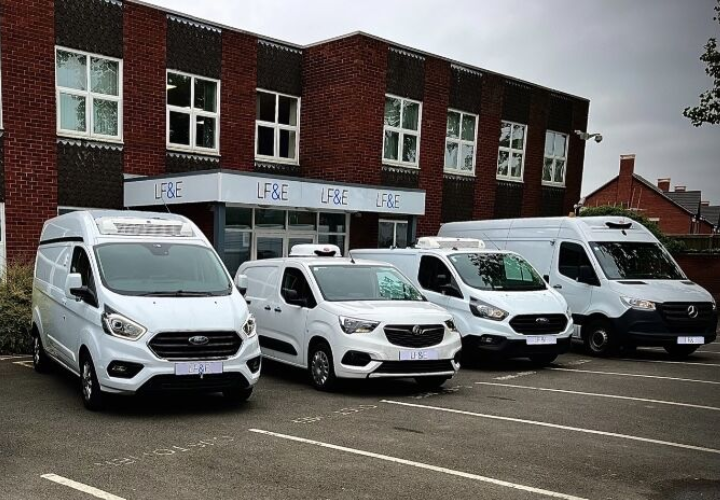 Modern fleet of delivery vans parked outside a logistics office, showcasing fleet management and vehicle tracking solutions from Microlise.