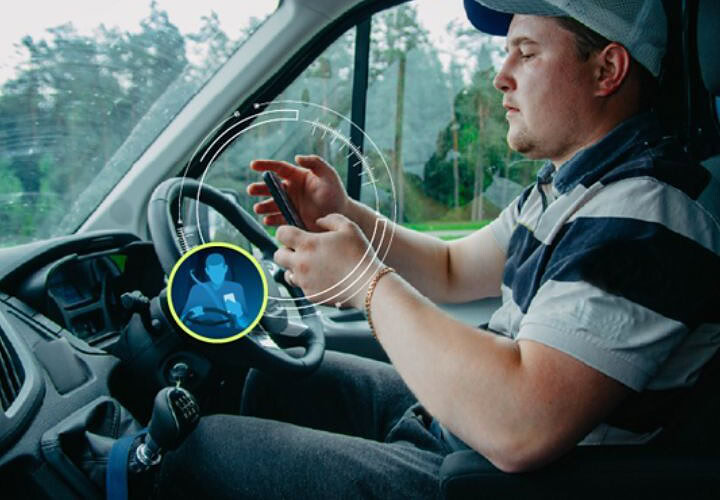 Distracted driver using smartphone behind the wheel, illustrating dangerous driving habits that can be identified and reduced for safer roads.