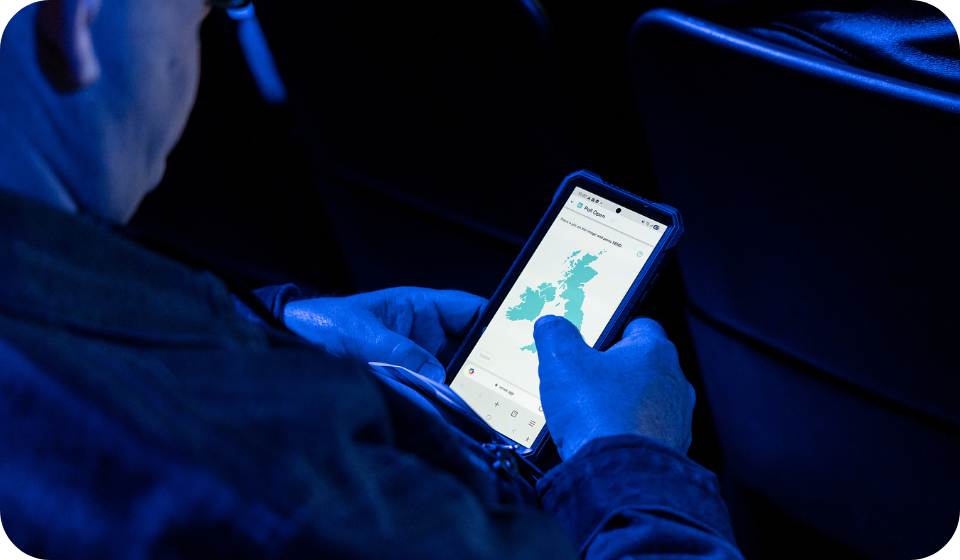 An SEO-friendly ALT tag: Business professional using a smartphone with logistics and fleet management app, focusing on real-time tracking and transportation solutions by Microlise.