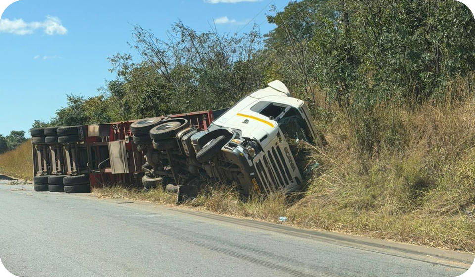 A truck has overturned on the side of a rural road, with the vehicle tilted into a grassy embankment and the cargo area partially off the road. The scene highlights the importance of fleet safety and.
