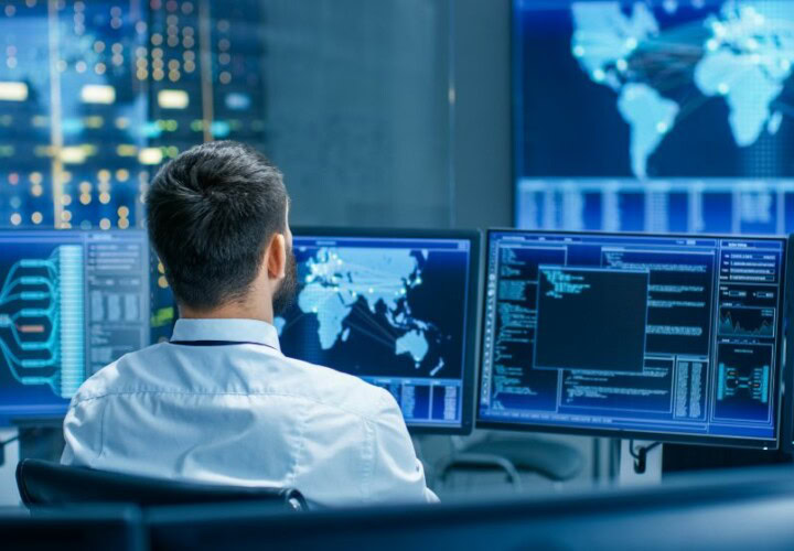 Professionnel analysant des données opérationnelles sur plusieurs écrans